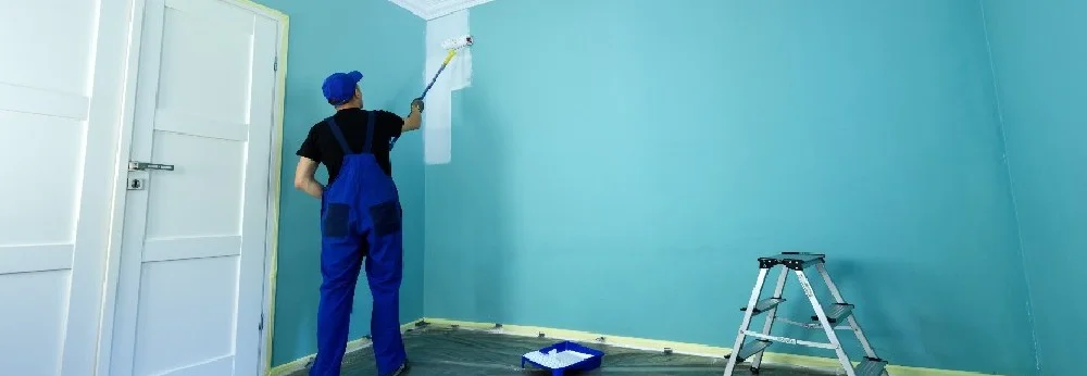 Person streicht Wand mit Farbrolle